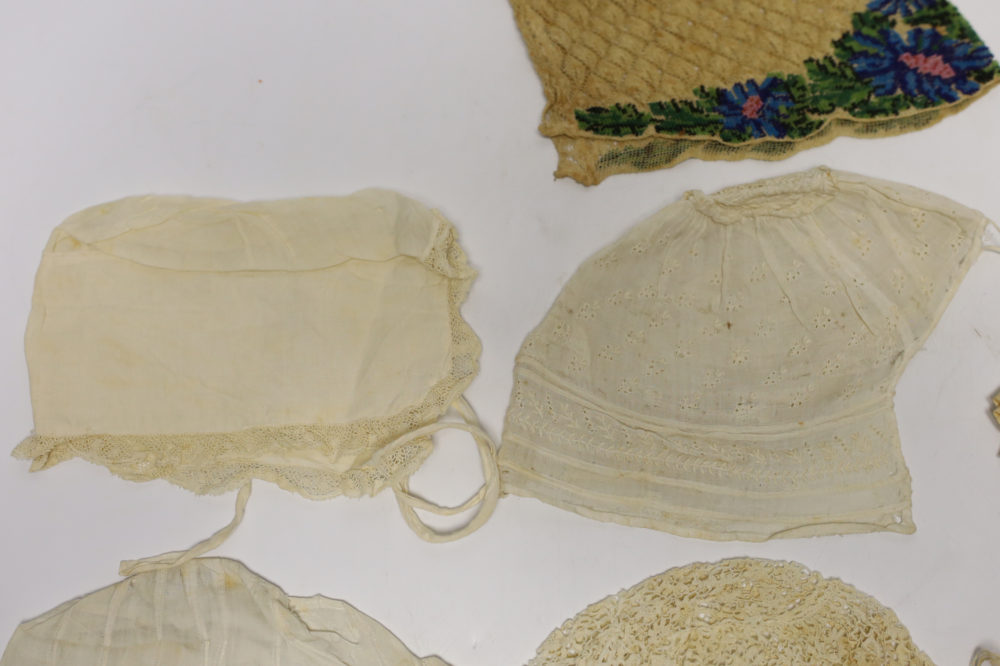 Seven baby bonnets, late 18th / 19th century, including a fine bobbin lace bonnet and unusual silk knitted and multi coloured floral designed beaded bonnet